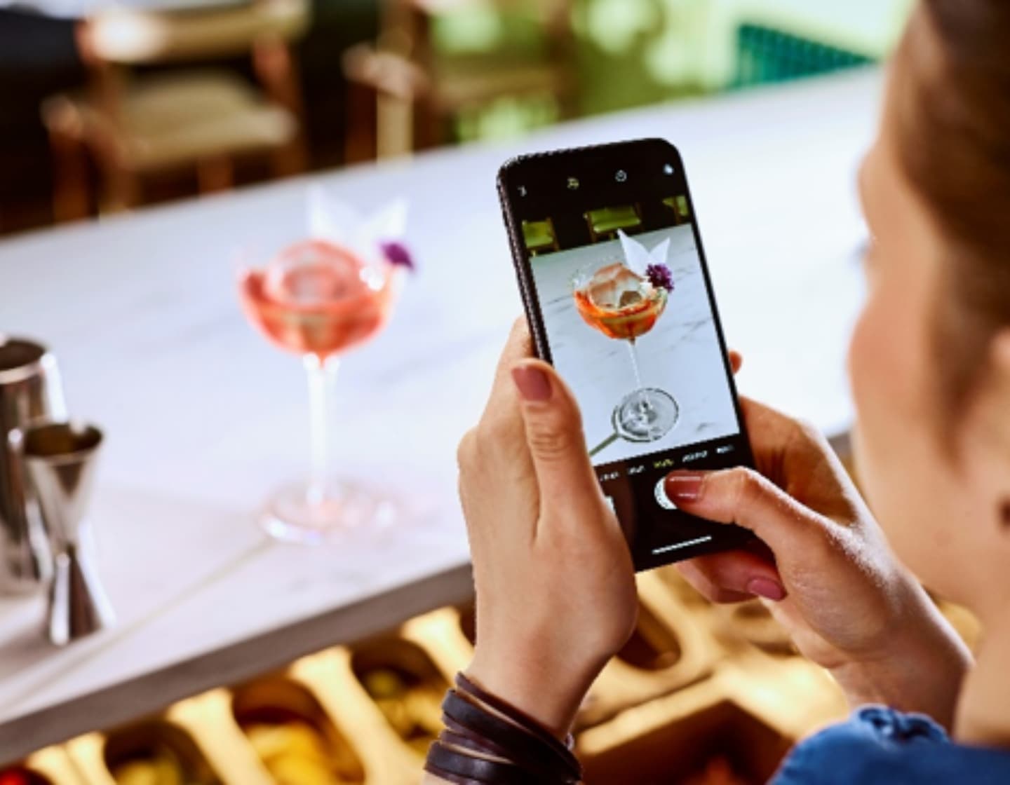 Bartender using phone to take photo of cocktail 